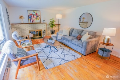 Living room with oversized entry windows, original hardwoods, and a wood burning fireplace