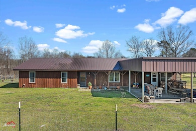 Rear view of house with metal roof, a yard, and a 