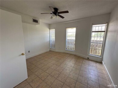 Unfurnished room featuring healthy amount of natural light, a textured ceiling, ceiling fan, and baseboards