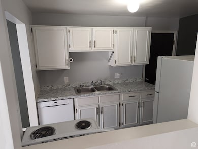 Kitchen featuring white appliances, light countertops, and white cabinets