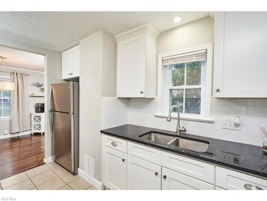 Kitchen with white cabinetry, a textured ceiling, tile floors, dark countertops, backsplash, and stainless steel refrigerator