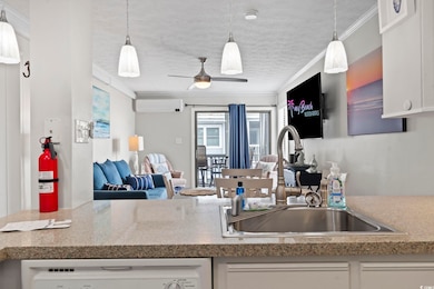 Kitchen with crown molding, hanging light fixtures, a ceiling fan, open floor plan, and white cabinets