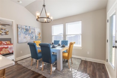Dining space featuring plenty of natural light, dark hardwood / wood-style floors, lofted ceiling, and an inviting chandelier