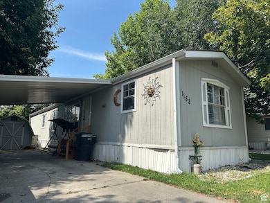 View of side of home with a storage unit, a carport, and concrete driveway