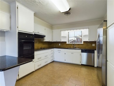 Kitchen with white cabinets, backsplash, ornamental molding, black appliances, and light tile patterned flooring