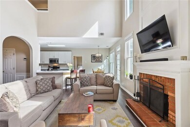 Living room featuring wood-type flooring, a high ceiling, and a brick fireplace