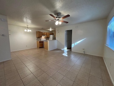 Unfurnished living room featuring a textured ceiling, a chandelier, a ceiling fan, and light tile patterned flooring