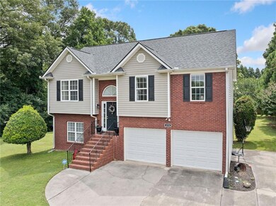 Bi-level home featuring a garage, driveway, a front lawn, brick siding, and a shingled roof