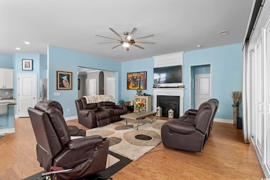 Living room featuring light wood-style floors, a ceiling fan, a glass covered fireplace, arched walkways, and recessed lighting