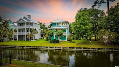 Back of property at dusk featuring a balcony, a water view, a lawn, and a sunroom