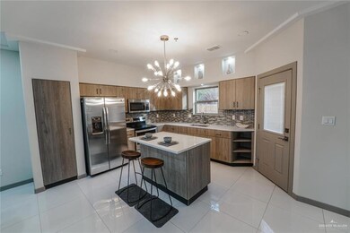 Kitchen featuring stainless steel appliances, tasteful backsplash, brown cabinetry, a chandelier, and light countertops