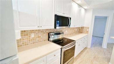 Kitchen featuring white cabinetry, light countertops, appliances with stainless steel finishes, and decorative backsplash