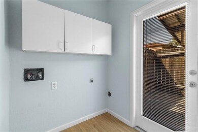 Laundry room with cabinet space, electric dryer hookup, baseboards, and light wood-style floors