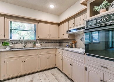Kitchen featuring oven, sink, tasteful backsplash, and light wood-type flooring
