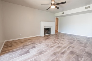Unfurnished living room with light wood finished floors, a fireplace, and ceiling fan