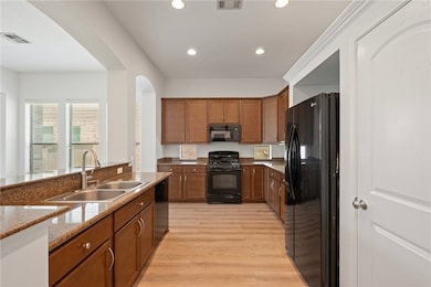 Kitchen featuring black appliances, brown cabinetr