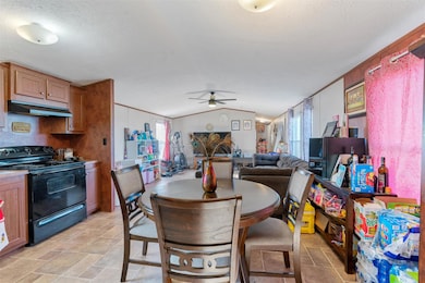 Dining room with vaulted ceiling, a ceiling fan, a textured ceiling, and crown molding