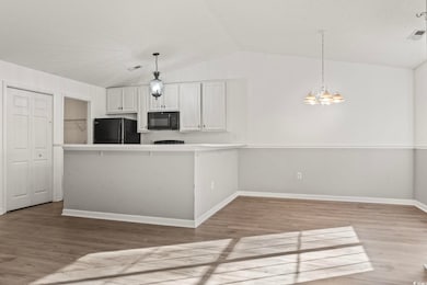 Kitchen with black appliances, vaulted ceiling, a 