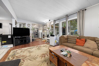 Living area featuring wood finished floors, vaulted ceiling, and a warm lit fireplace