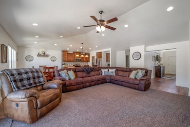 Carpeted living room with recessed lighting, vaulted ceiling, and a ceiling fan