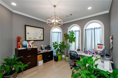Office with a chandelier, light wood-style flooring, and ornamental molding
