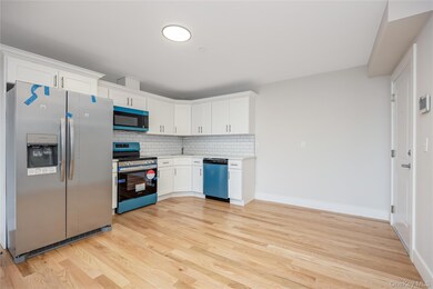 Kitchen with appliances with stainless steel finishes, tasteful backsplash, light wood-style flooring, and white cabinetry
