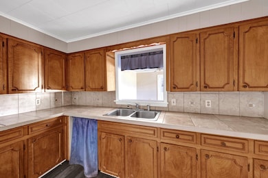 Kitchen featuring decorative backsplash, brown cabinetry, and ornamental molding