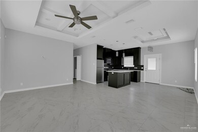 Unfurnished living room with ceiling fan, a tray ceiling, sink, and light tile floors