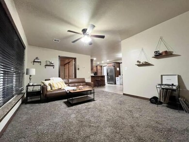 Carpeted living room with ceiling fan