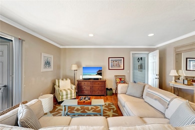 Living area with ornamental molding, wood finished floors, and recessed lighting