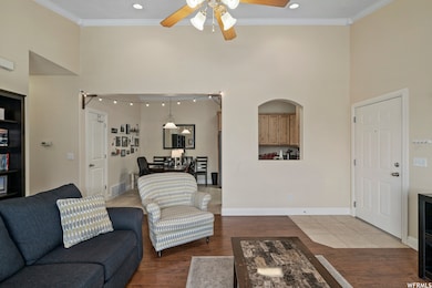 Living area featuring a high ceiling, wood finished floors, crown molding, a ceiling fan, and recessed lighting