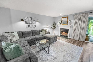 Living room with wood finished floors and a glass covered fireplace