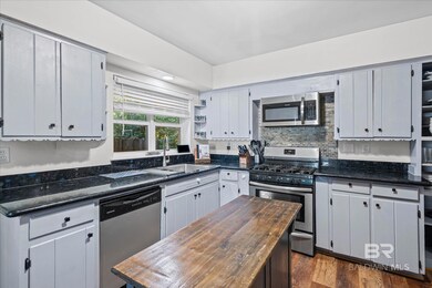 Kitchen featuring open shelves, stainless steel appliances, dark wood-style flooring, white cabinetry, and dark stone countertops