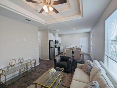 Living area featuring dark wood-style flooring, a tray ceiling, a ceiling fan, and recessed lighting