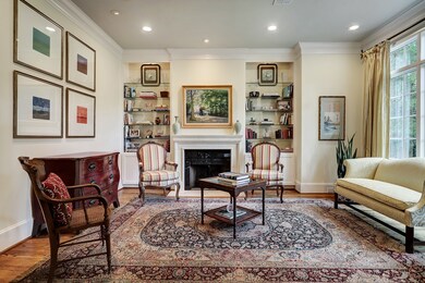 Formal living room adjacent to entry and dining features a gaslog fireplace with stone mantle and granite surround, built-ins with glass shelving and Casement windows allowing for great natural light.