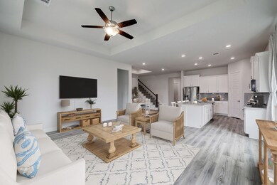 The living room is a roomy and inviting space featuring large windows that flood the area with natural light and provide scenic views. A ceiling fan enhances comfort and circulation, making this room a perfect place to relax and unwind.




