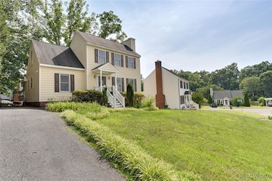 Colonial-style house with a front yard, a chimney, and roof with shingles