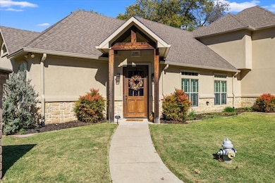 View of front facade featuring stone siding, a front lawn, stucco siding, and a shingled roof