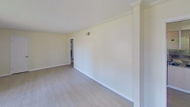 Spare room with wood finished floors, ornamental molding, and baseboards