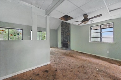Empty room featuring a ceiling fan and lofted ceiling