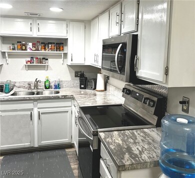 Kitchen with a textured ceiling, white cabinets, s