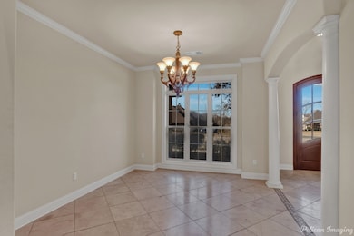 Unfurnished dining area with a chandelier, light tile patterned floors, decorative columns, crown molding, and arched walkways