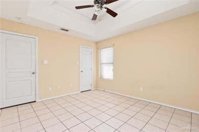 Unfurnished room featuring visible vents, a raised ceiling, baseboards, and a ceiling fan
