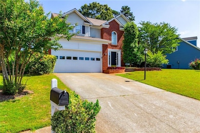 Traditional-style house featuring concrete driveway, brick siding, a front yard, and an attached garage