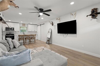 Living room with light wood-style floors, recessed lighting, a barn door, and ceiling fan