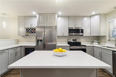 Featuring stainless steel appliances, stone counters and an island with an overhang