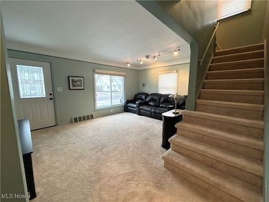 Living room with carpet floors, stairs, and rail lighting
