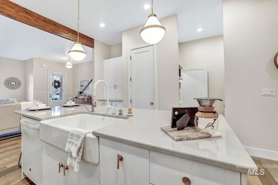 Kitchen with light wood-type flooring, white cabinets, open floor plan, light stone counters, and white dishwasher