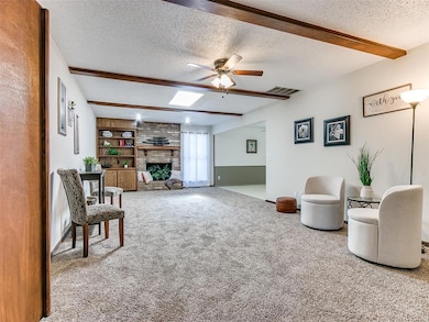 Carpeted living room with beam ceiling, a fireplac