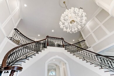 This breathtaking chandelier perfectly sits between the two story walls that are adorned with custom wood detailing